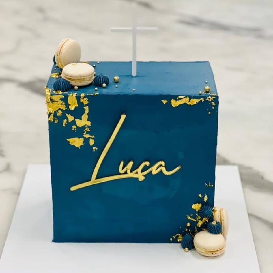 Custom decorated cake available at Brunetti Classico Carlton. Wall cake, square cake, decorated with gold leaf and navy butter cream. Embellished with name plate and macarons. Baptism cake, baby shower cake, confirmation cake.