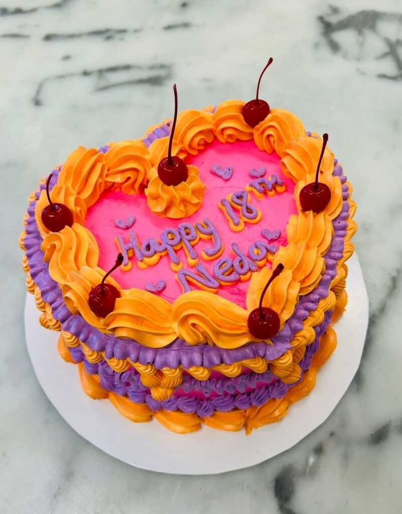 Custom decorated cake available at Brunetti Classico Carlton. Heart shape, retro vintage style buttercream decorated cake. 18th birthday party cake with cherries and buttercream. Birthday party cake, heart shaped cake