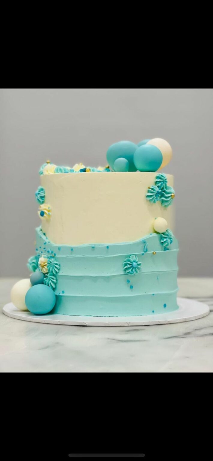 Custom decorated cake available at Brunetti Classico Carlton. Blue textured striped buttercream with chocolate sphere decoration. 2023 cake trend, 1st birthday party, boys birthday party, gender reveal party