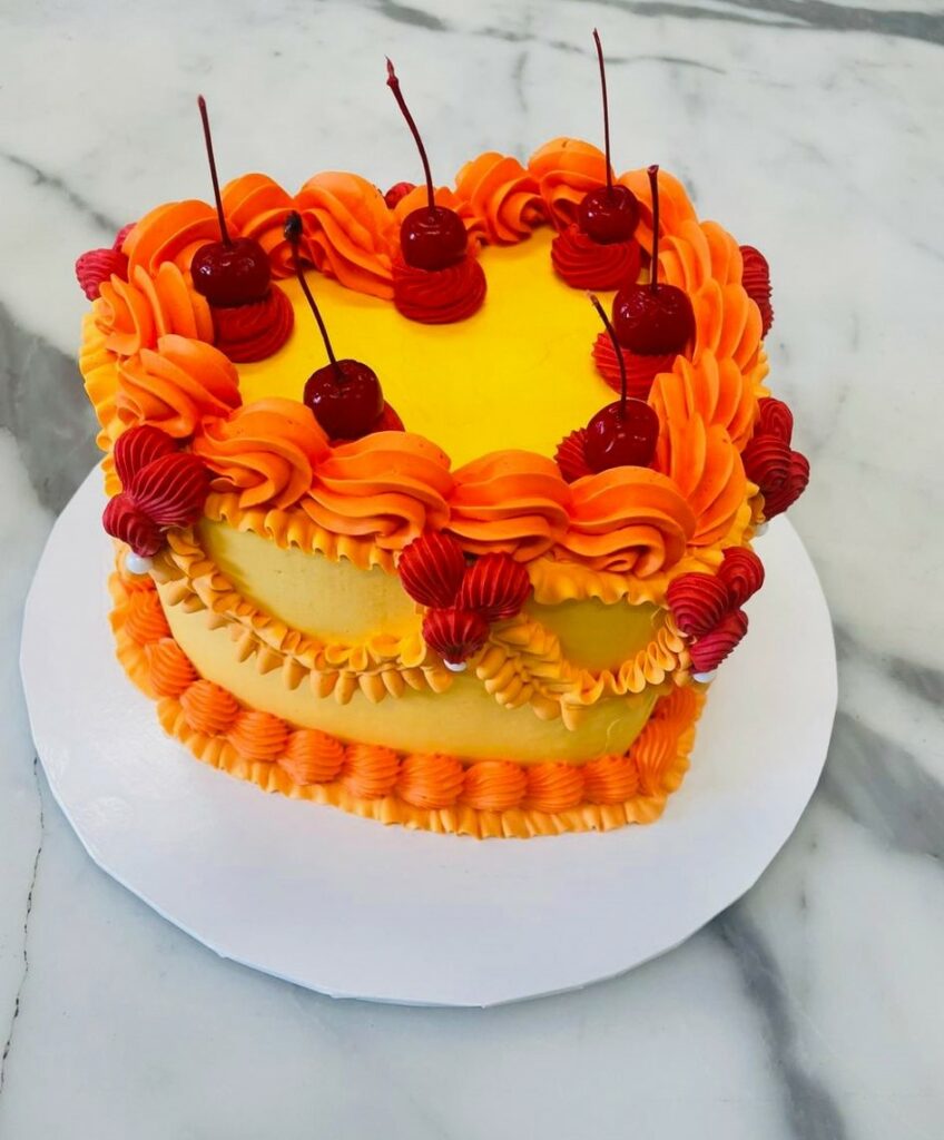 Custom decorated cake available at Brunetti Classico Carlton. Heart shape, retro vintage style buttercream decorated cake. 18th birthday party, 21st birthday party, anniversary, engagement party, valentines cake with cherries and buttercream. Birthday party cake, heart shaped cake